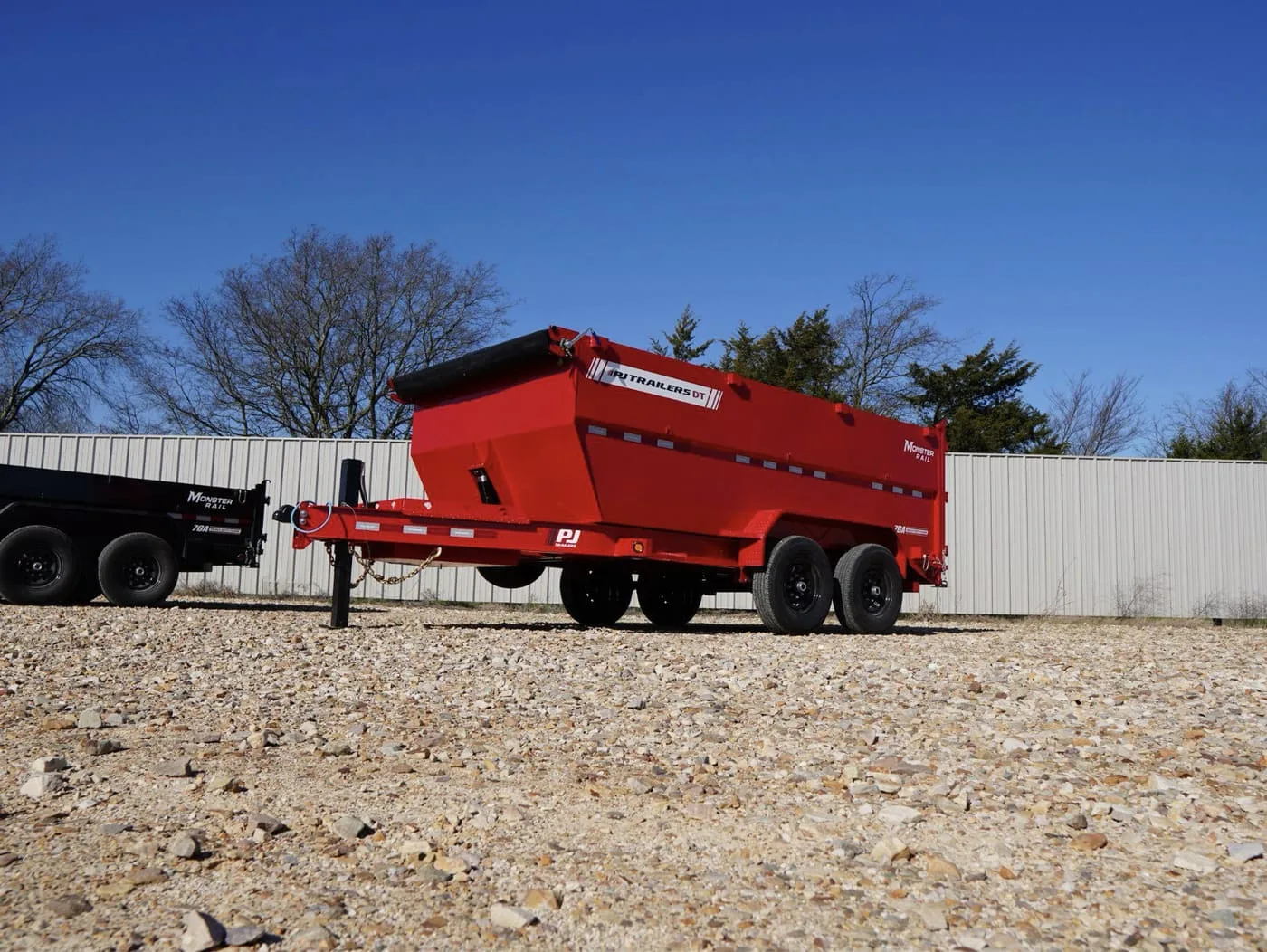 PJ’s 5-Stage Dump Trailer in a parking lot in front of a white fence