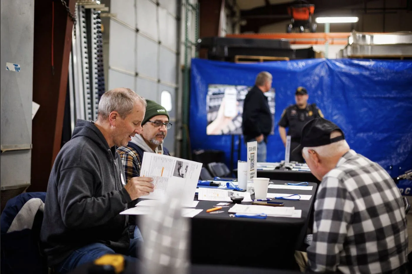 People sitting at a Table in trailer repair shop watching a presentation