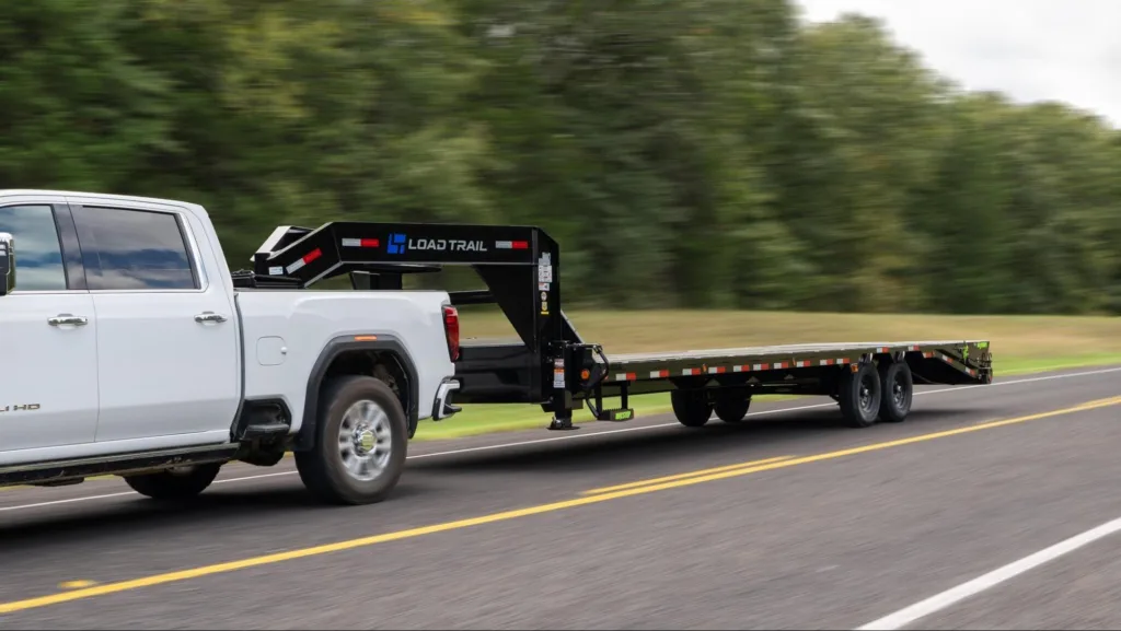 Load Trail Gooseneck Trailer being hauled down a road by a white pickup truck